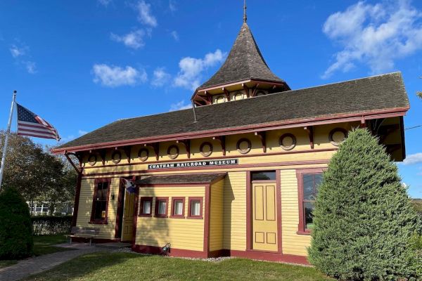 The image shows a historic building labeled “Eastport Ross Park Museum” with a U.S. flag and clear blue skies in the background.