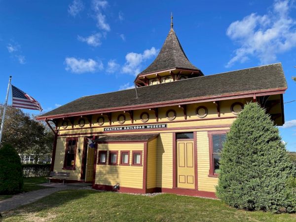 The image shows a historic building labeled “Eastport Ross Park Museum” with a U.S. flag and clear blue skies in the background.