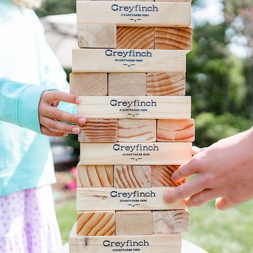 Two people are playing a game with wooden blocks labeled 