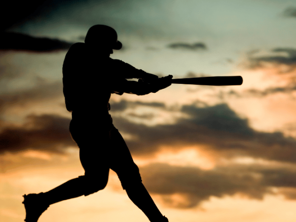A silhouetted soldier aims a rifle at the horizon during a dramatic sunset over clouds.