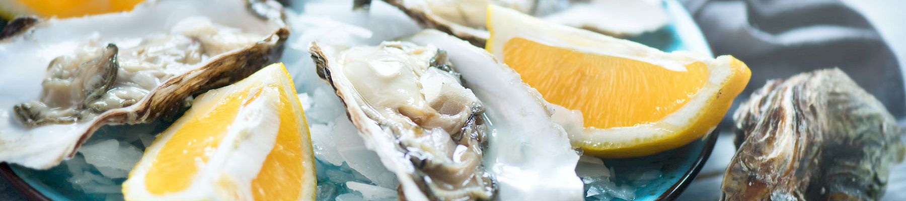 Fresh oysters on a bed of ice, topped with lemon wedges, for a chilled seafood platter.