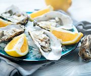 Fresh oysters on a bed of ice, topped with lemon wedges, for a chilled seafood platter.
