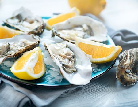 Fresh oysters on a bed of ice, topped with lemon wedges, for a chilled seafood platter.