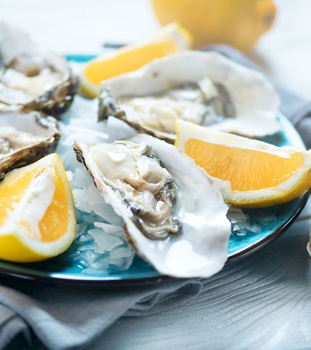Fresh oysters on a bed of ice, topped with lemon wedges, for a chilled seafood platter.