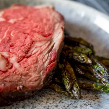 A plate with a juicy cooked steak and a side of grilled asparagus spears, ready to eat.